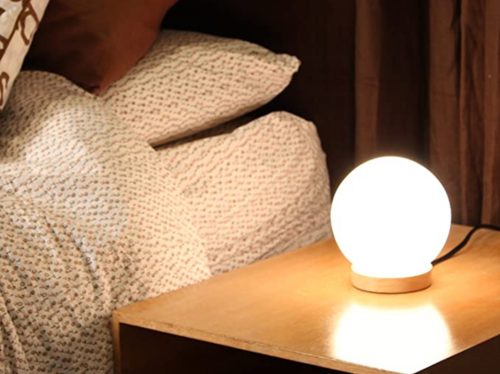 Lampe de table boule de verre Iris sur table de chevet près du lit