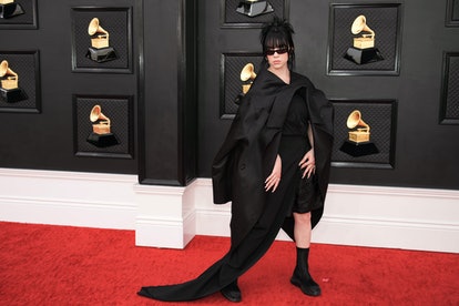 Billie Eilish porte une robe asymétrique noire avec des chaussures à plateforme sur le tapis rouge des Grammys 2022.